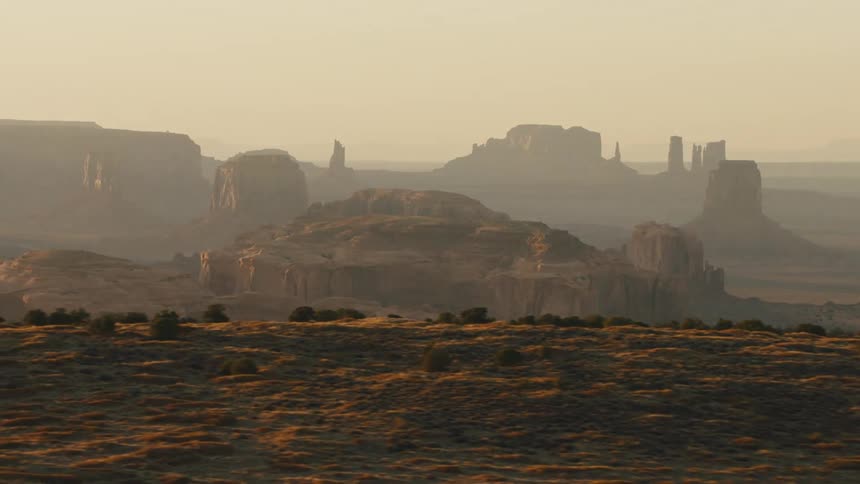 Flat land and mesas sit in the fog under a cloudy sky