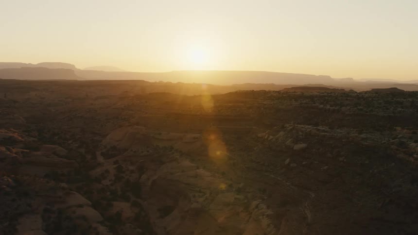 Aerial view of the sun going down behind the hills