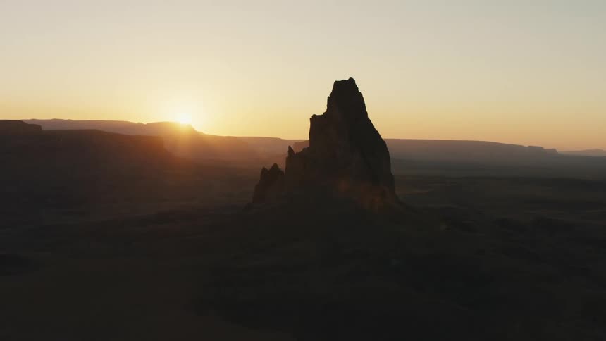 Aerial view of a tall eroded mountain on the badlands desert at sunset