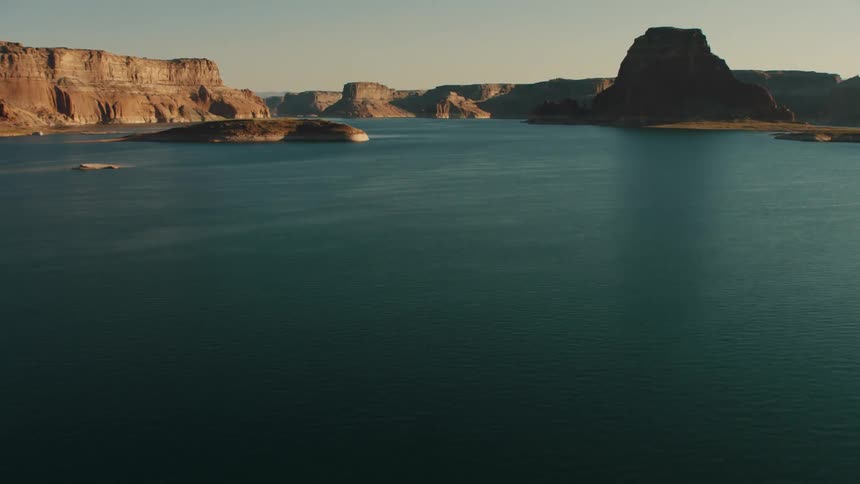 A calm lake with deep blue water is surrounded by cliffs
