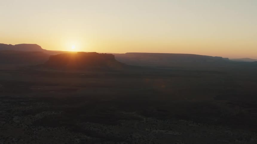 Sun on horizon turns sky red and glares across rough terrain