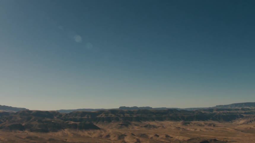 Bare ground stretches to mountains on horizon