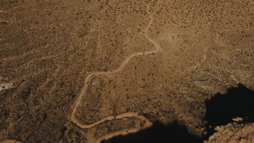 Helicopter casts shadow on the desert while flying overhead