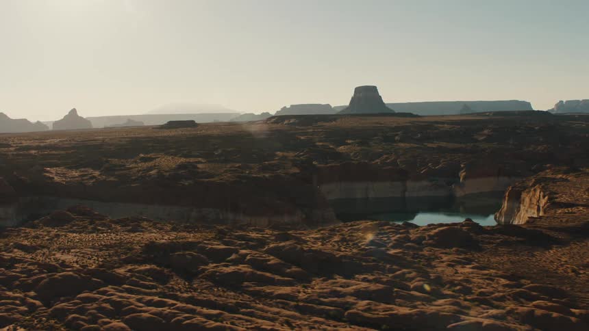 A desert with a pond and plateaus and the sky in the background