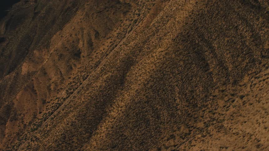 A desert with hills and mountains with the sky and clouds in the background