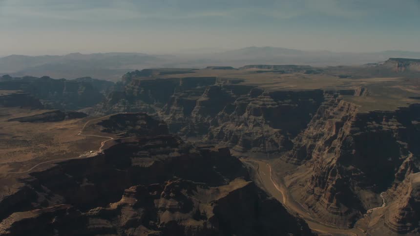 Aerial view of a river flowing at the bottom of a canyon between mesas in the desert badlands