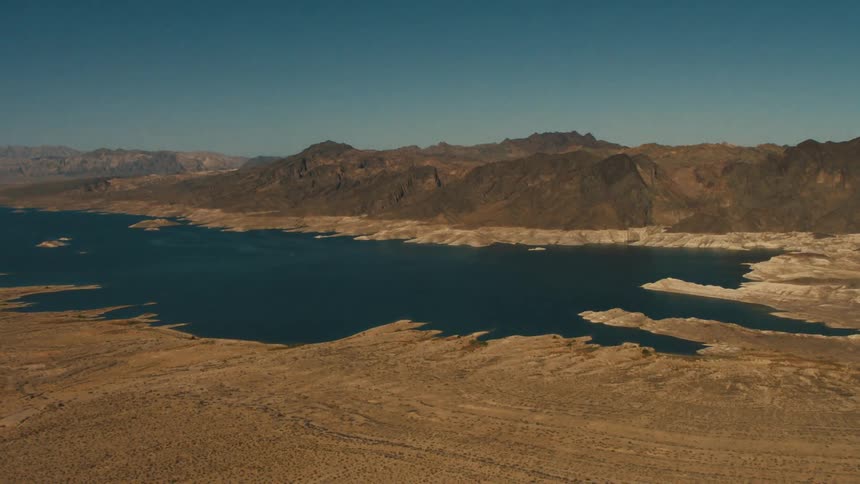 The long field leads to the water by the mountain
