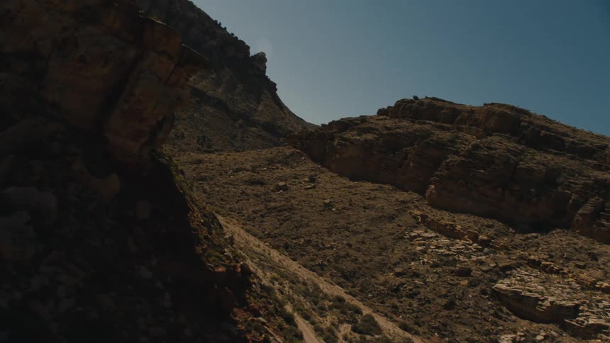 A canyon with rocks plants and the sky in the background