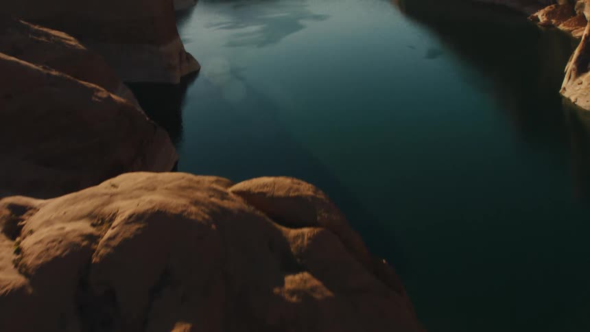 A dark river running through a ravine in the badlands during the day