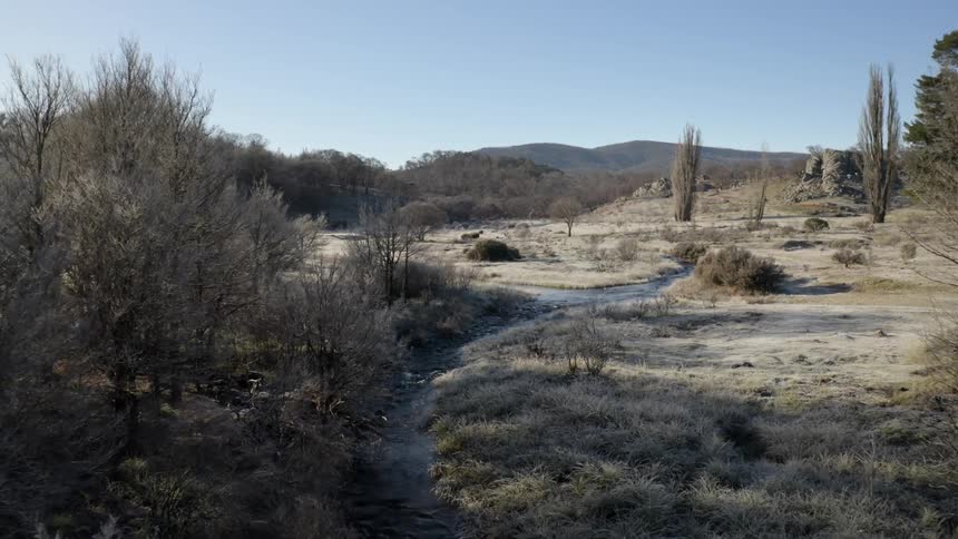 A stream running through a countryside of pale grass