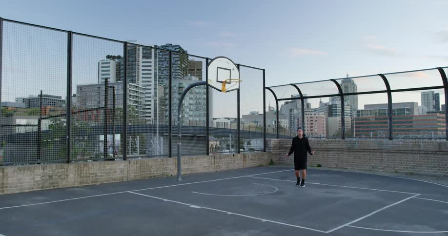 A man is jumping rope on the rooftop basketball court