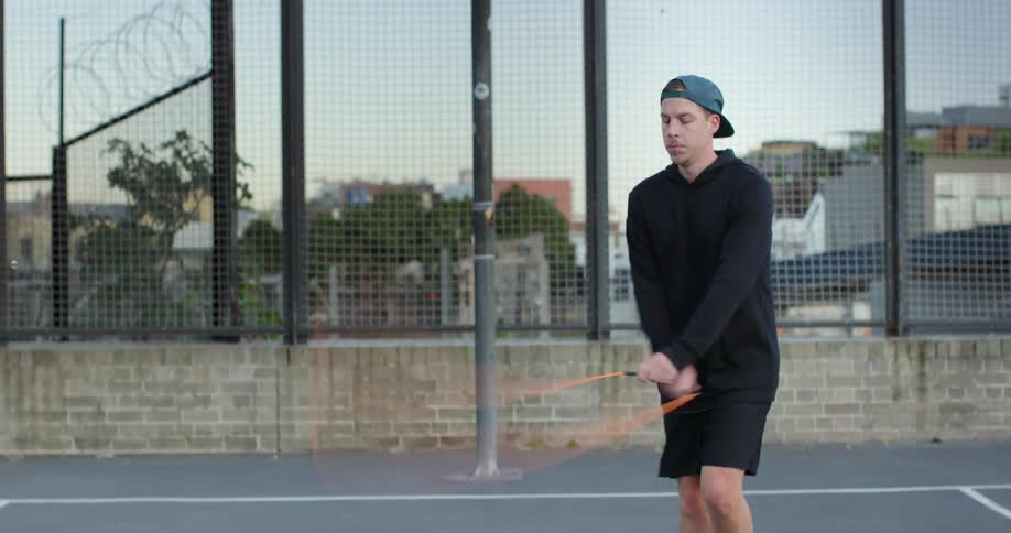 Man jumping rope in a basketball court in the city at sunset