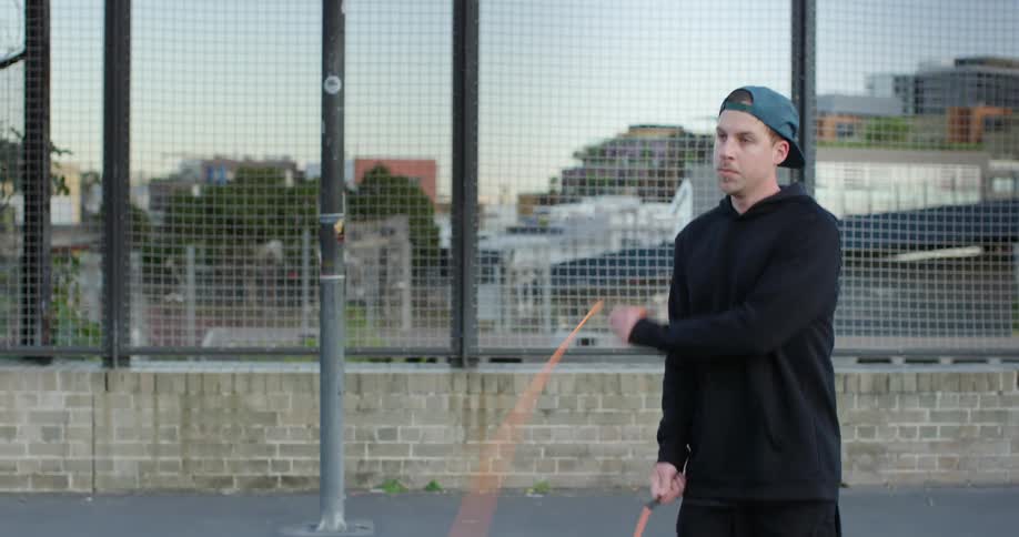 Man jumping rope on outdoor basketball court in city