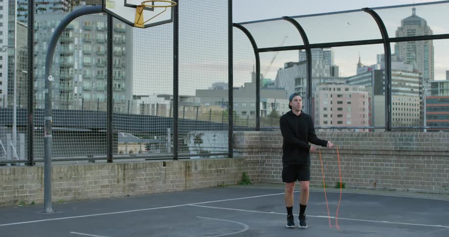 A man jumps rope on a city roof top basketball court