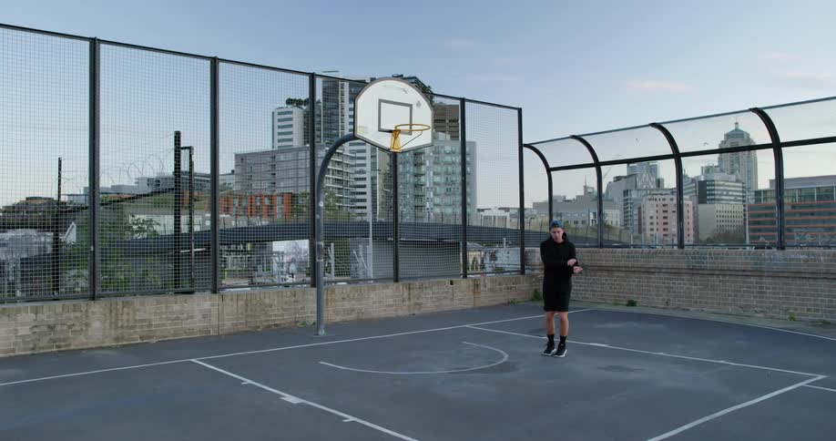 Man jumping rope in a basketball court in a city at sunset