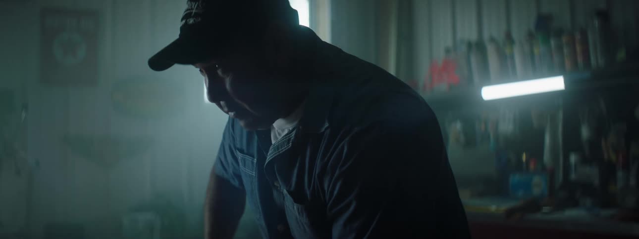 Mechanic works on an engine in a dimly lit workshop