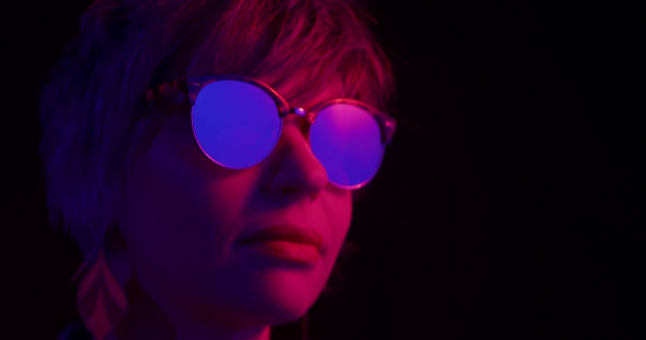 Woman putting on round sunglasses with mirrored lenses