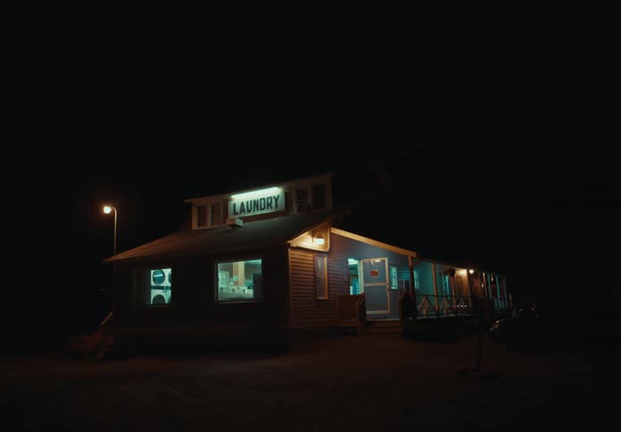 A laundromat at night with a streetlight on one side and vehicles on the other
