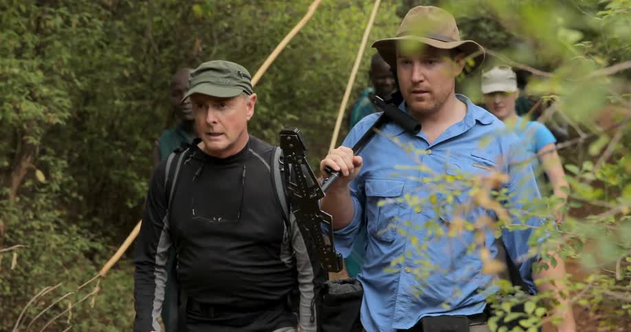 A group of men walk through a forested area