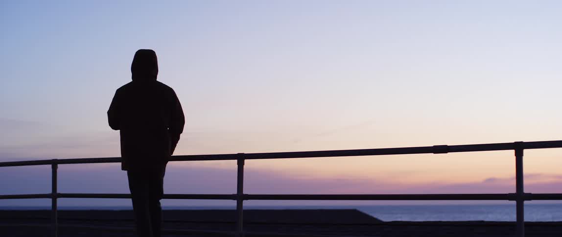 A person walks on the boardwalk at sunset