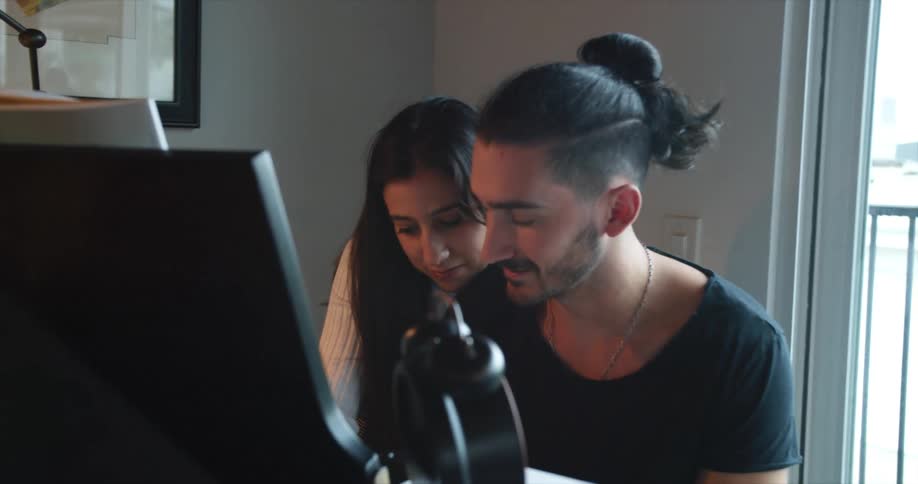 A man and a woman sitting down in front of a piano