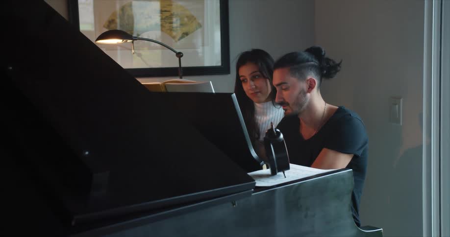 A man and woman are playing a piano