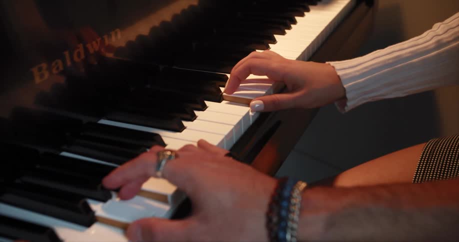 Hands playing duet on upright piano