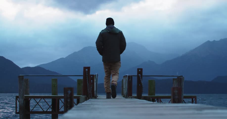 A man is walking on a dock that is above the lake