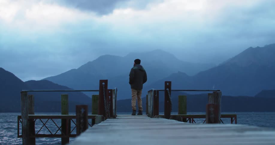A man walks on a dock out into a lake