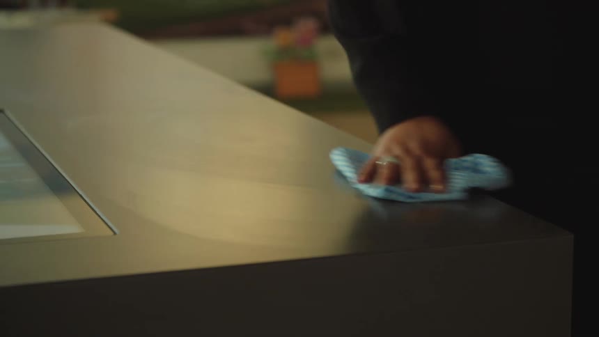 Female holding a spray bottle of cleanser uses a handy wipe to clean the formica of the counter