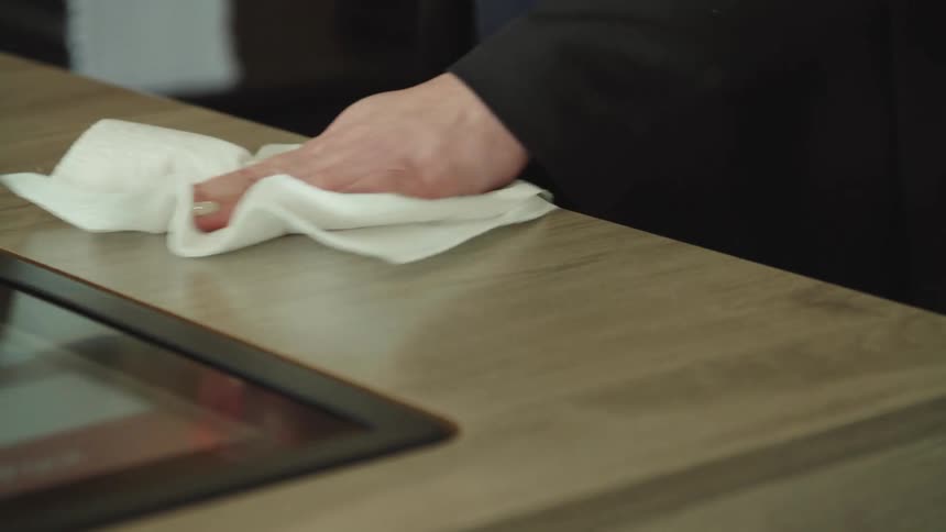 A person with a spray cleaner and a paper towel cleaning a counter