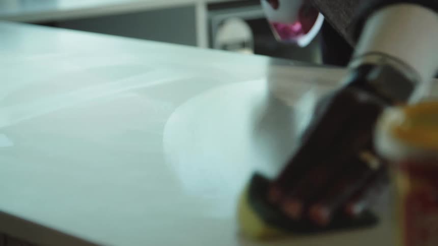 Man sprays counter then wipes it off with sponge