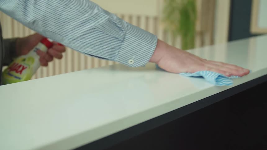 Person sprays cleaner then wipes counter with cloth