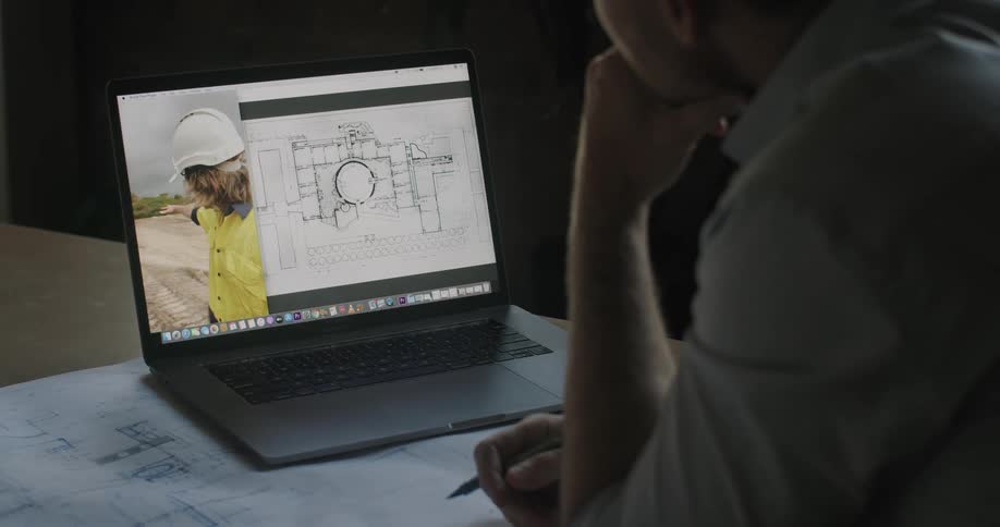 A man with a pen in his hand in front of a laptop at a desk video chatting