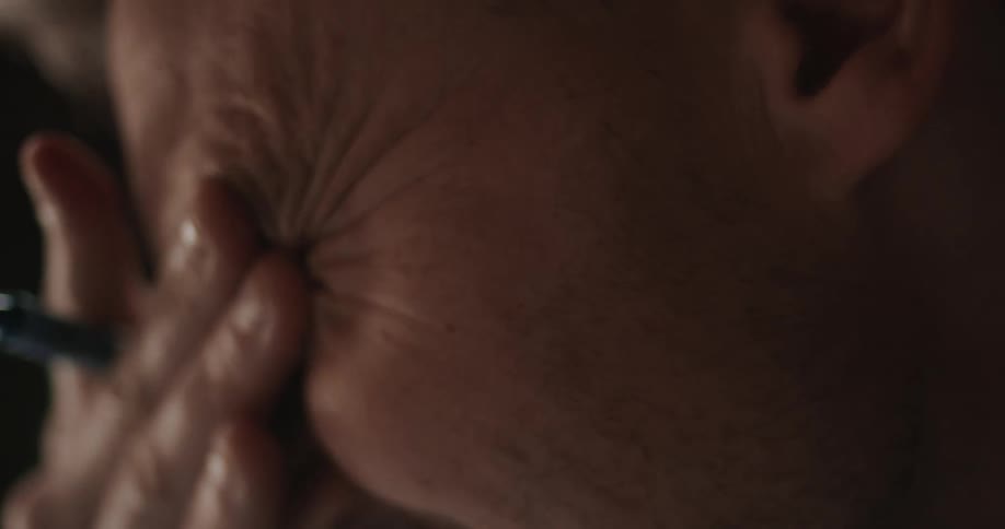 Working man stops to rub eyes with hand holding pen
