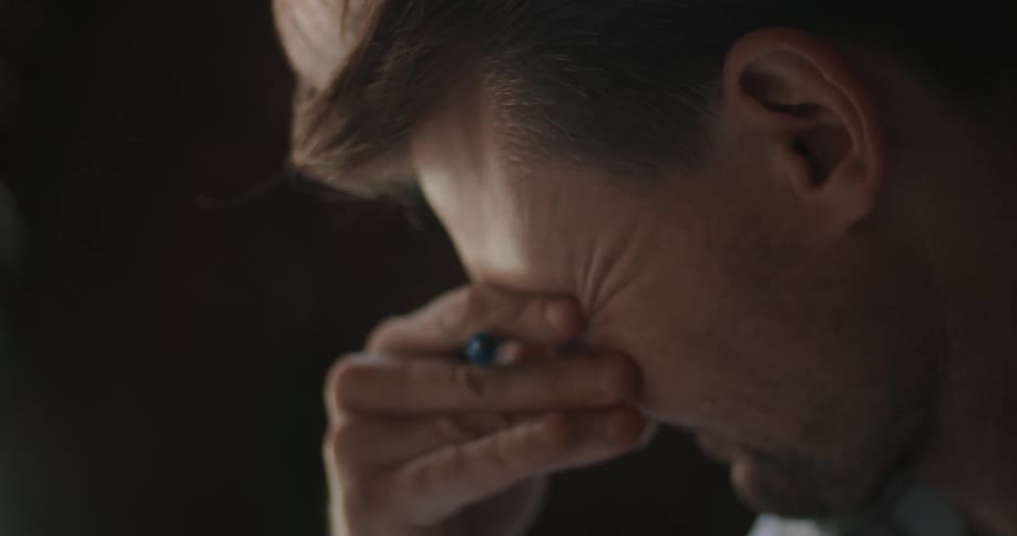 A man is working and rubs his face