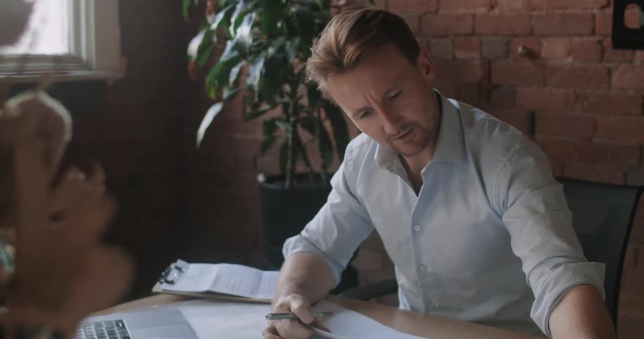 A man looks at a blue print and talks to a person on his laptop