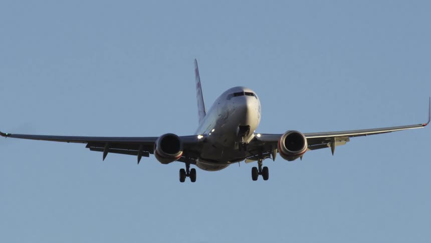 Airplane flies in clear blue sky with landing gear out