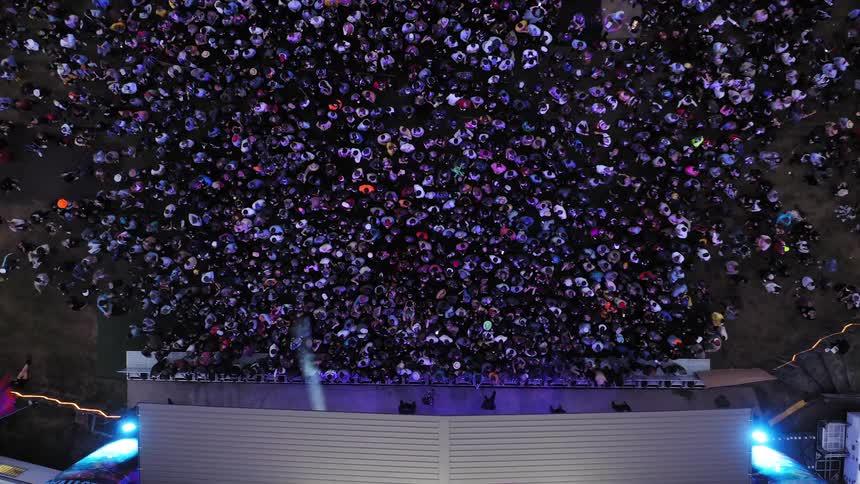 People standing in front a stage in a concert with lights flashing