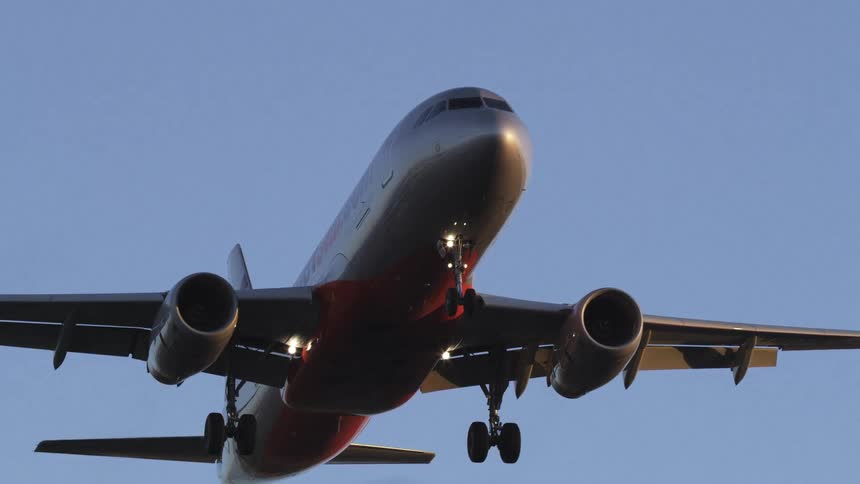 Airliner flies overhead against a blue sky