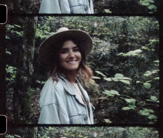 Woman wearing a sun hat turns and smiles while standing outdoors
