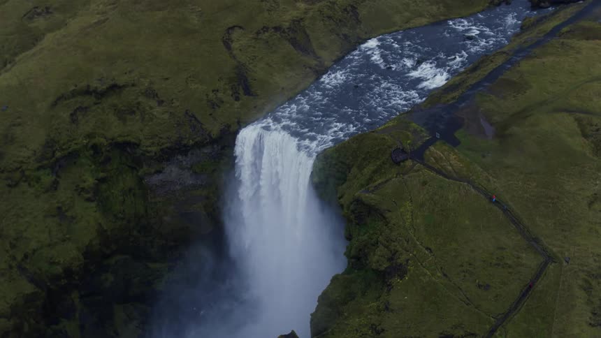 Hikers walk along path toward wide waterfall