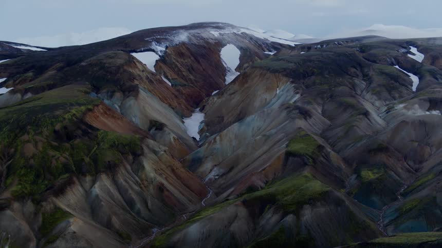 Color mountains with snow and vegetation interspersed among the ridges
