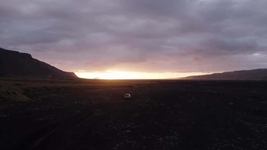 A vehicle is driving off road at sunset