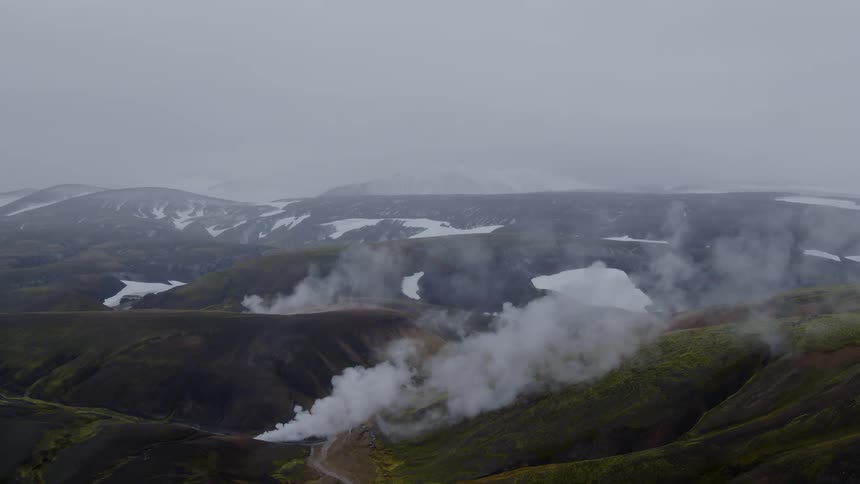 Rain falls onto mountainous terrain covered by fog