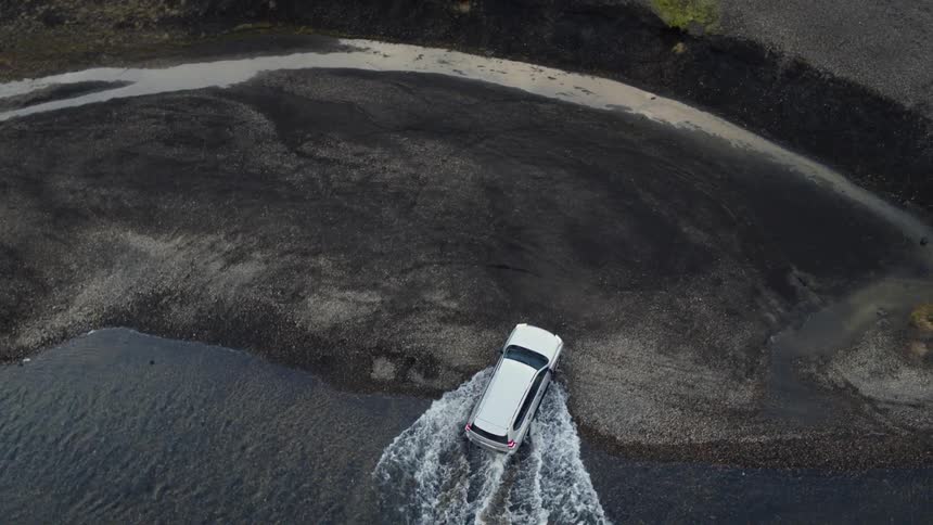 The vehicle drives through the stream water