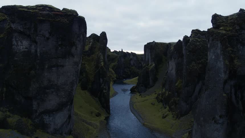A canyon with a river with the sky and clouds in the background
