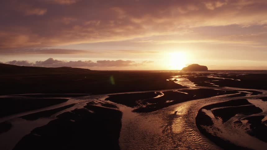 The low sun springs on a field of winding and crisscrossing streams on a plain