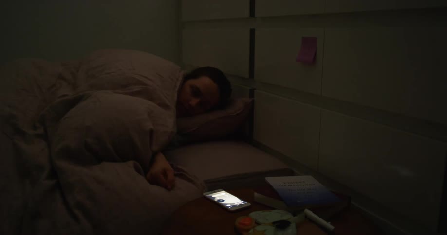 A man is at home sleeping in bed and his phone rings and he picks it up