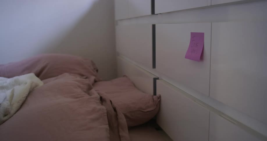 A room with a draw with a note on it next to a bed with sheets